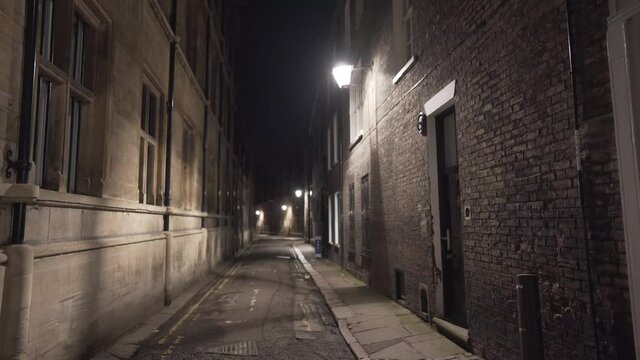 Narrow street alley illuminated in cambridge city centre england uk. Scary passage with yellow light during the night