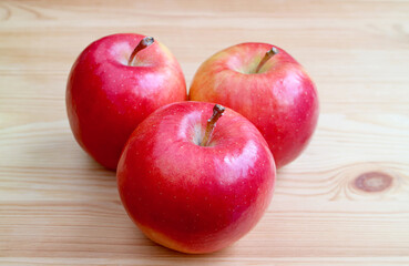 Three of fresh ripe red apple isolated on wooden table