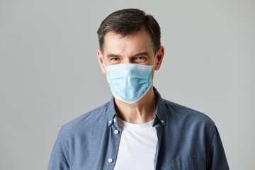 Senior wearing a protective face mask isolated on gray background in studio