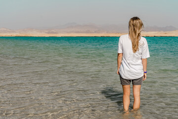 Back view of woman on clear lake in desert of Ras Mohammed. Egypt