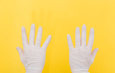 The close plan. Two hands in white medical gloves on a yellow background. The medicine. Place for an inscription. Medical gloves. Advertising. Covid 19.