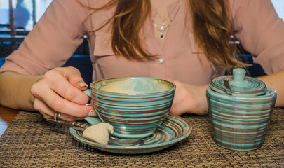 Lady holding cup of coffee standing on the table