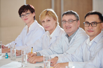 Researchers attending medical conference, taking notes and looking at camera