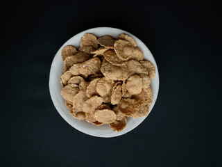 Breakfast cereals, multi-grain flakes in a clay plate on a beautiful black background.  Food concept.