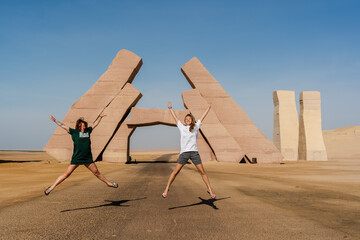 Fototapeta premium Girls jump near huge Gate of Allah, Ras Mohammed national park in Egypt. Desert