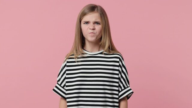 Displeased crying little blonde kid girl 12-13 years old in striped t-shirt isolated on pink background studio. Childhood lifestyle concept. Covering ears with fingers keeping eyes closed screaming