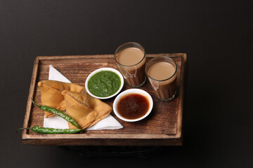 Indian snack Homemade spicy and delicious samosa served with green, tamarind chutney cutting masala tea, chai, 