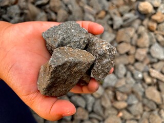 A small child’s hand holding several pebbles