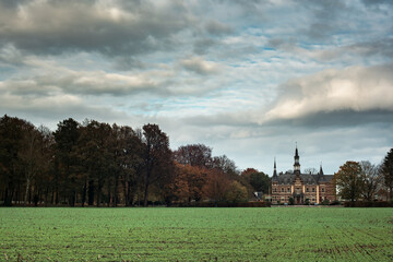 Fototapeta na wymiar Arable field with country house and autumn trees under cloudy sky.