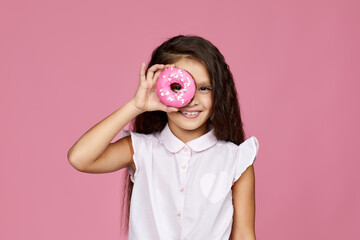 smiling child girl holding yummy donut isolated on pink background.