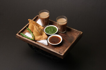 Indian snack Homemade spicy and delicious samosa served with green, tamarind chutney cutting masala tea, chai, 