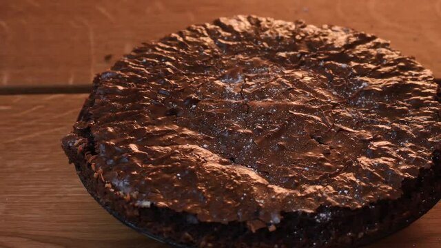 Home baked chocolate cake on wooden table. Icing suger being sprinkled over the cake. The cake is a classic traditional Swedish cake, known as Kladdkaka.