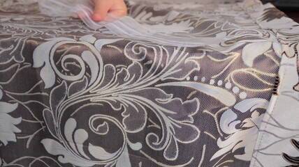 A female hand applies a tape to the curtains fabric, close-up.