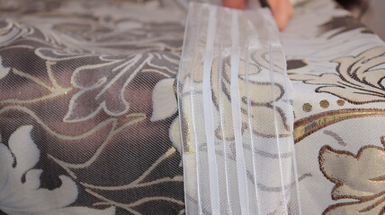 A female hand applies a tape to the curtains fabric, close-up.