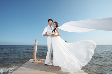 Fototapeta na wymiar Young Couple in Wedding Dress on beach