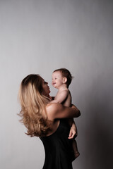 Mother plays with her little son. Grey background. Free copy space.