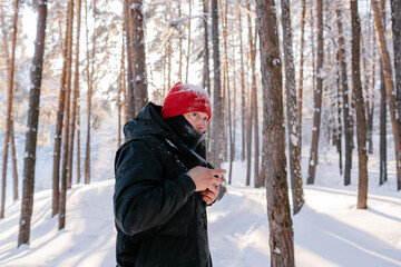 Fototapeta na wymiar Young man takes photos in winter forest