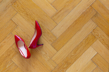 Red leather women's shoes on a classic herringbone parquet floor with space for text - 407036475