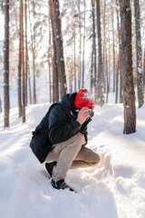 Fototapeta na wymiar Young man takes photos in winter forest