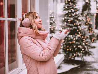 girl catches snowflakes and smiles cute on Christmas markets in winter