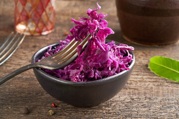 Red fermented cabbage on a fork in a bowl