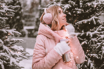 a young girl stands in the forest and looks up dreamily, holding a thermos in her hands woman in the forest