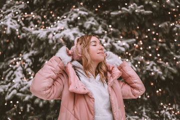 portrait of young a girl with closed eyes is smiling and in the background she has a Christmas tree and it is snowing