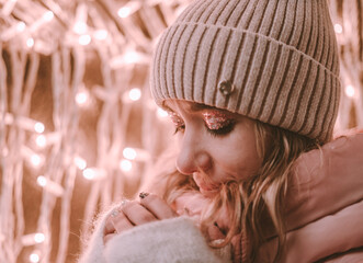 portrait of a young girl looking down in a winter hat on the street and holding a mug in her hands