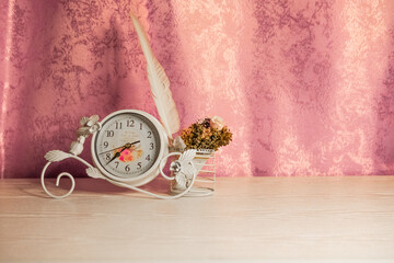 Vintage clocks with bouqet and birds feather is standing on the table in the girls bedroom before the Valentine's Day