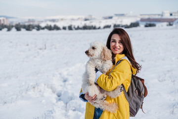 backpacker woman hiking outdoors with cute poodle dog. Snowy mountain in winter season. nature, pets and lifestyle
