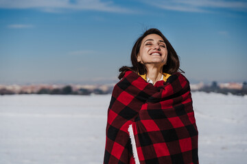 happy woman hiking outdoors in snowy mountain. Wrapped in plaid blanket. Nature and lifestyle