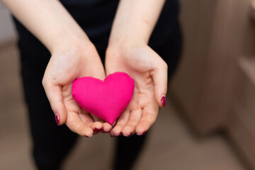 Female hands giving red heart. A woman with a heart shaped ball in her hand.