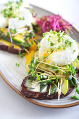 Toasts with microgreens, avocado, asparagus and poached egg. Vertical photography. .