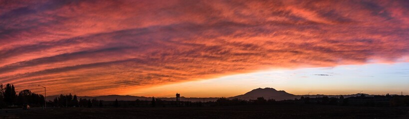 Panoramic views of a colorful sunset in East San Francisco Bay Area, with brightly colored clouds covering the sky, and Mt Diablo visible on the horizon; Contra Costa County, California