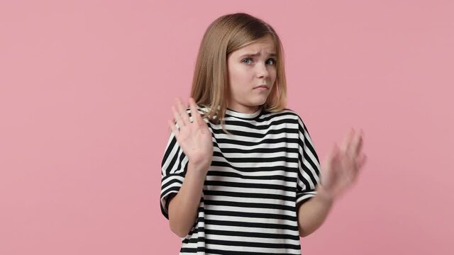 Confused puzzled little blonde kid girl 12-13 in striped t-shirt isolated on pink background studio. Childhood lifestyle concept. Pointing fingers herself ask say who me no thanks i do not need it