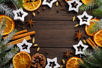 Christmas or New Year background. Fir branches with dried orange, cardamom and mulled wine spices, sprinkledon dark wooden background. Place for your text.