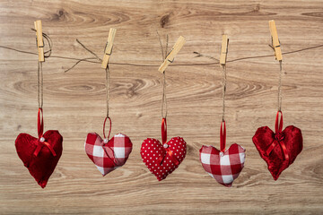 Textile hearts hanging on rope on wooden background.