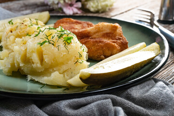 Pork chop served with mashed potatoes and pickled cucumber.