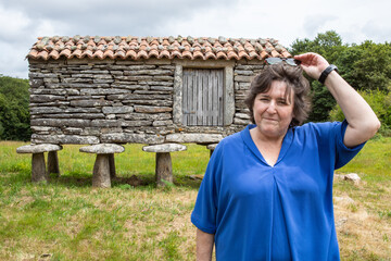 lady posing in front of a Galician Hórreo.
He wears a blue shirt and sunglasses