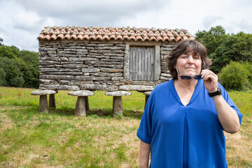 Fototapeta premium lady posing in front of a Galician Hórreo. He wears a blue shirt and sunglasses