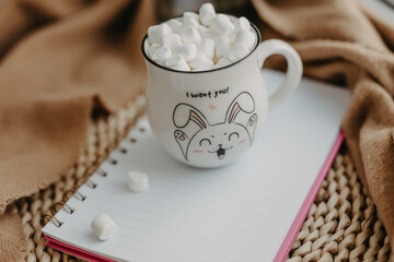 Hot chocolate with marshmallow and cinnamon, clean blank notebook. Cup for Valentine's Day.
