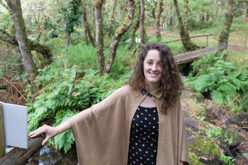 
portrait of a woman on a small wooden bridge in a green forest.
He wears a dark bib and a brown...