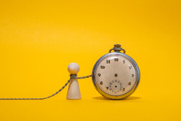 Prisoner of time concept. Wooden figure and vintage clock on yellow background - Powered by Adobe