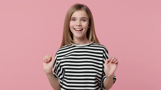 Cheerful little kid girl 12-13 in striped t-shirt isolated on pink background. Childhood lifestyle concept. Sleep with folded hands under cheek waking up stretching arms waving greeting with hand