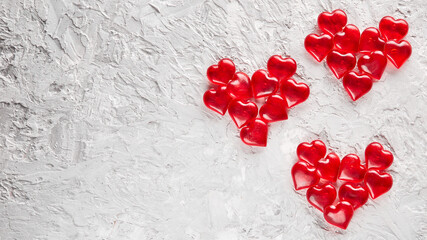 Background with red hearts, Valentine's Day celebration concept. A red glass heart is laid out along the edge of the image on a white textured background. Layout with space for your text