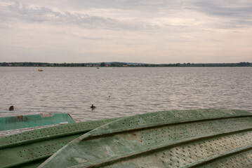 Naklejka na ściany i meble Abstract view on lake Jamno, Mielno, Poland. Old green fishing boats in the foreground. Selective focus. 