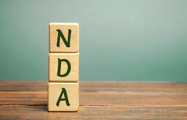 Wooden blocks with the word NDA - Non disclosure agreement. A legal contract entered into by two...