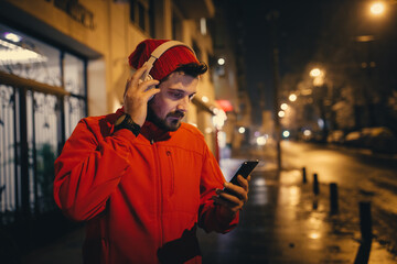 Sports man using mobile phone on winter night at street
