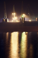 Fototapeta na wymiar Bulk carrier unloading at a foggy night.