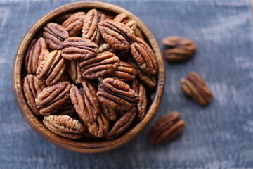 Pecan nut close-up in a round wooden cup on a black  board on wooden table background.Nuts and seeds. .Healthy fats.Heap shelled Pecans nut closeup.keto diet.Tasty raw organic food snack